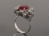 a close up of a ring with a red stone surrounded by white diamonds