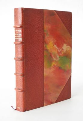 an old book with a red cover sitting on top of a white surface