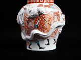 a white vase with a red and orange design on it