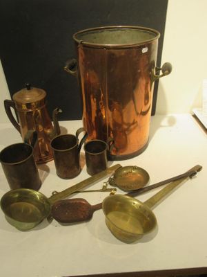a lot of copperware on a table next to a blackboard