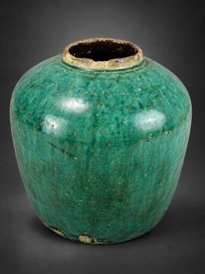 un vase vert posé sur une surface noire