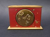 a small red and gold clock on a black table