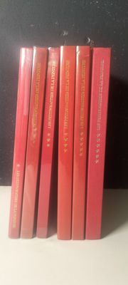 six livres rouges posés sur une étagère blanche, près d'un mur noir