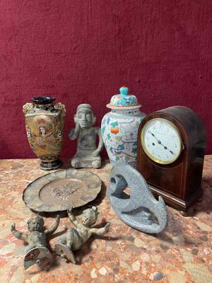 a table with a clock, figurines, and other items on it