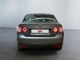 the back end of a silver car in a room with a white wall