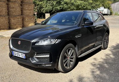 the black jaguar suv is parked in front of a hay bale