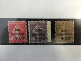 Trois timbres différents, provenant de pays différents, sont exposés sur une table.