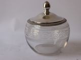 a glass jar with a silver lid on a white surface