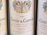 three bottles of red wine are lined up on a shelf