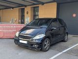 une voiture noire garée dans un parking à côté d'un bâtiment