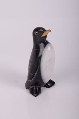 une petite figurine de pingouin en noir et blanc posée sur une surface blanche
