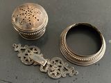 une petite boîte en argent et un petit objet en argent posés sur une table