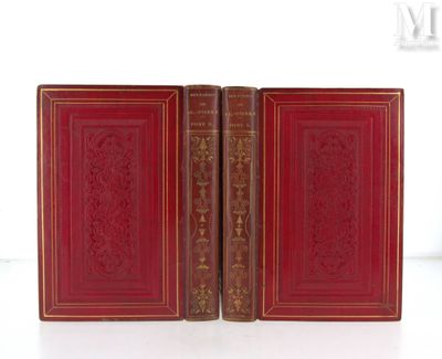 Deux livres rouges aux tranches dorées sont posés sur une surface blanche.