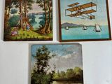 trois tableaux accrochés à un mur blanc, dont l'un représentant un avion et un bateau
