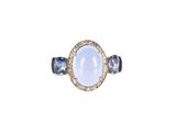 a close up of a ring with a white stone and blue sapphires
