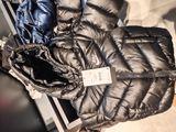 a black puffy jacket and a blue jacket on the floor