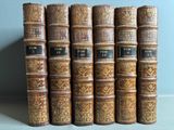 several old books are lined up in a row on a table