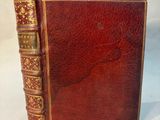un vieux livre à la couverture rouge posé sur une table blanche