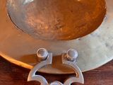 a metal bowl on a wooden table with a metal handle