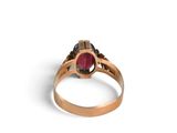 a close up of a gold ring with a red stone