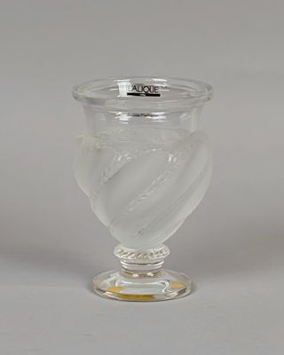 un vase en verre transparent muni d'un couvercle argenté, posé sur une surface blanche