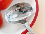 a plate with a spoon and some tomatoes on it
