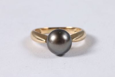 un gros plan d'une bague en perle noire posée sur une surface blanche