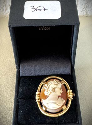 an image of a gold plated broochee with a woman ' s face in it