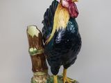 a figurine of a rooster standing on a tree branch
