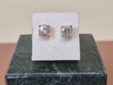 a pair of diamond stud earrings sitting on top of a marble block