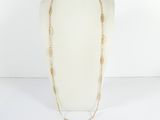 a white mannequin with a gold chain and a long necklace