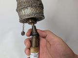 a person holding a metal bell with a chain around it