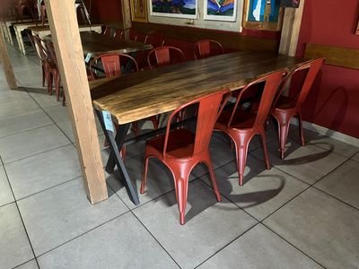 des tables et des chaises dans une pièce aux murs rouges, avec un tableau accroché au mur