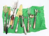 many different types of silverware on a green cloth