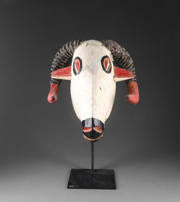 un masque blanc et rouge muni de cornes, posé sur un socle noir