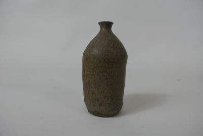 un vase brun posé sur une surface blanche