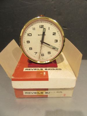 une horloge posée sur une boîte, elle-même posée sur une table