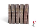 several old books are lined up on a shelf on a white surface