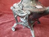 a silver tea pot sitting on a stand on a red cloth