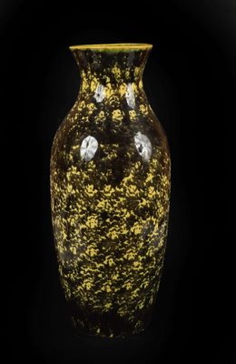 un vase jaune et noir posé sur une surface noire