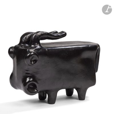 une petite statue de vache noire posée sur une surface blanche