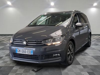 La Volkswagen Touran est garée dans une grande pièce au sol carrelé.