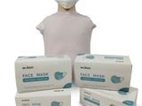 a person wearing a face mask next to three boxes of disposable face masks
