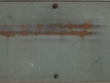 a metal plate with rust on it on a wall