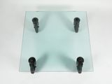 a glass table with three black legs and a glass top