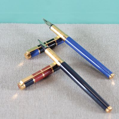 two pens sitting on top of a table next to each other