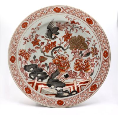 une assiette rouge et blanche décorée d'un oiseau et de fleurs