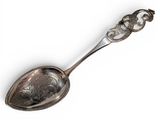 an antique silver spoon with a decorative handle on a white surface