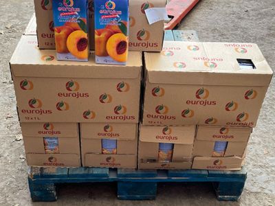 several boxes of fruit are stacked on a pallet on the ground