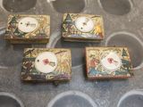 quatre petites boîtes ornées de visages, posées sur une table